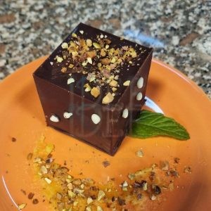 Cubo di cioccolato che nasconde zabaione colante, ganache fondente e crumble agli amaretti: dessert sorpresa ispirato a Amaury Guichon.